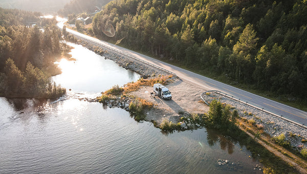Campervan with accessories parked next to water and forest