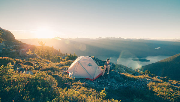 man camps with tent over beautiful view using solar generators uk to power devices