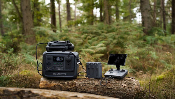 BLUETTI Portable power station charging drone equipment in a forest.